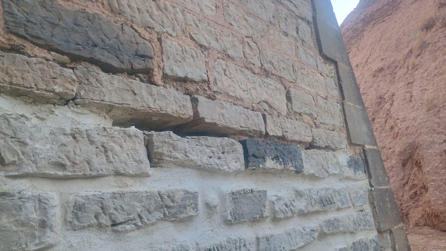 Detalle de un muro de piedra con la parte inferior ya rejuntada