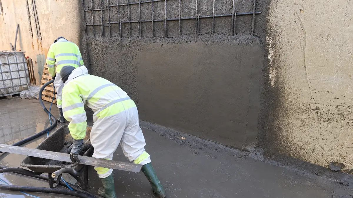 Operarios aplicando material sobre un muro de una instalación